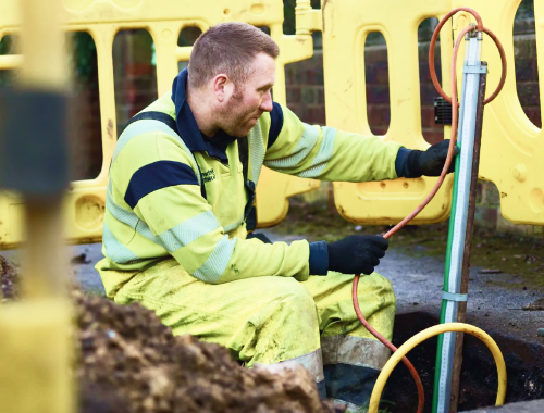 Northern Gas worker looking at pipes on building site