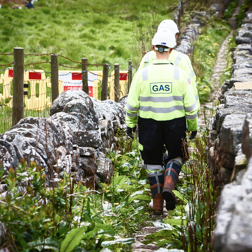 Northern Gas workers walking alongside stone wall in countryside