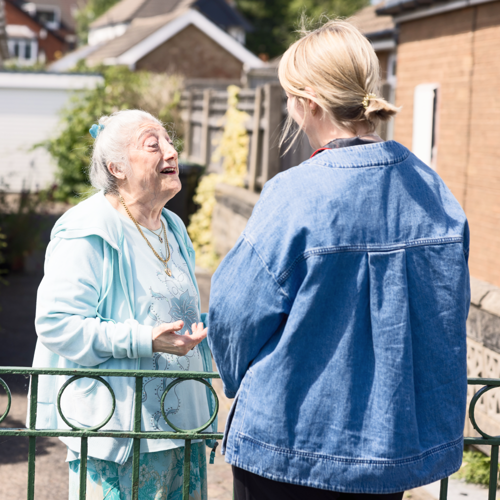 Older lady chatting to younger lady outside home
