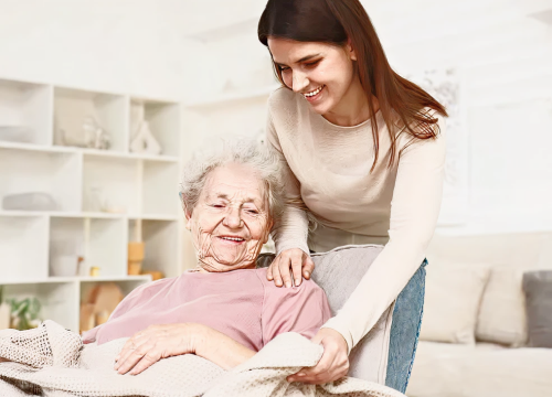 Older lady in wheelchair being assisted by woman standing above her