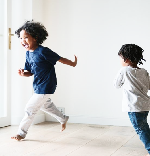 Two young children running around a living room