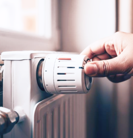 Hand turning knob on thermometer on radiator