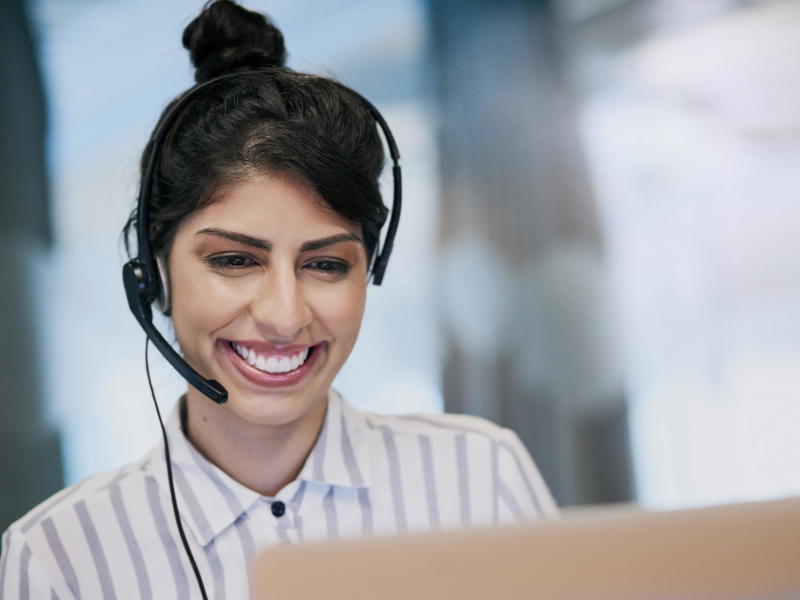Image of a women with headset on and talking to a customer.