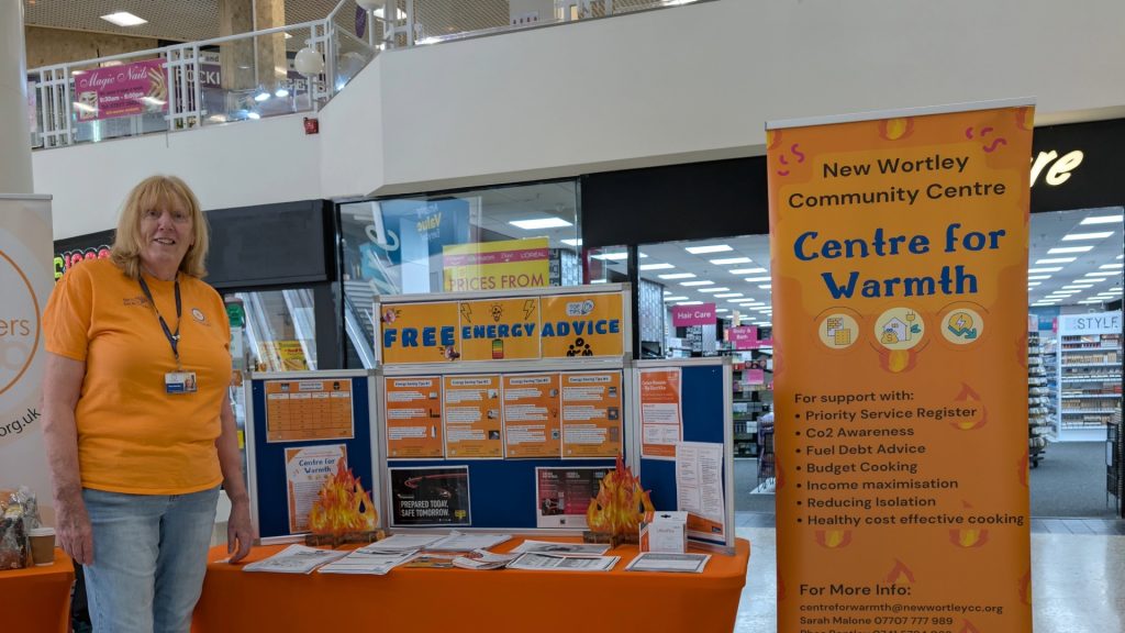 Women in local shopping centre with exhibition stand to promote free energy advice and New Wortley Centre for Warmth.