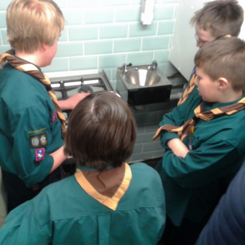 Image of four boy scouts gathered around a gas hob.