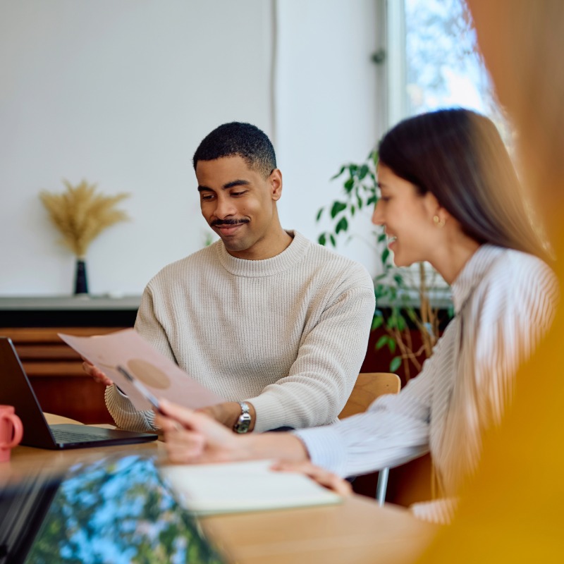 Image of two people meeting and reviewing project paperwork.