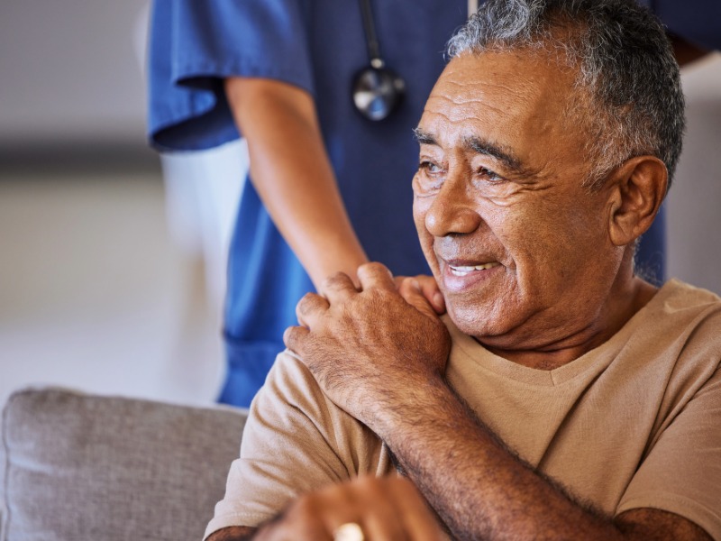 Image of male cancer patient holding hand of nurse.