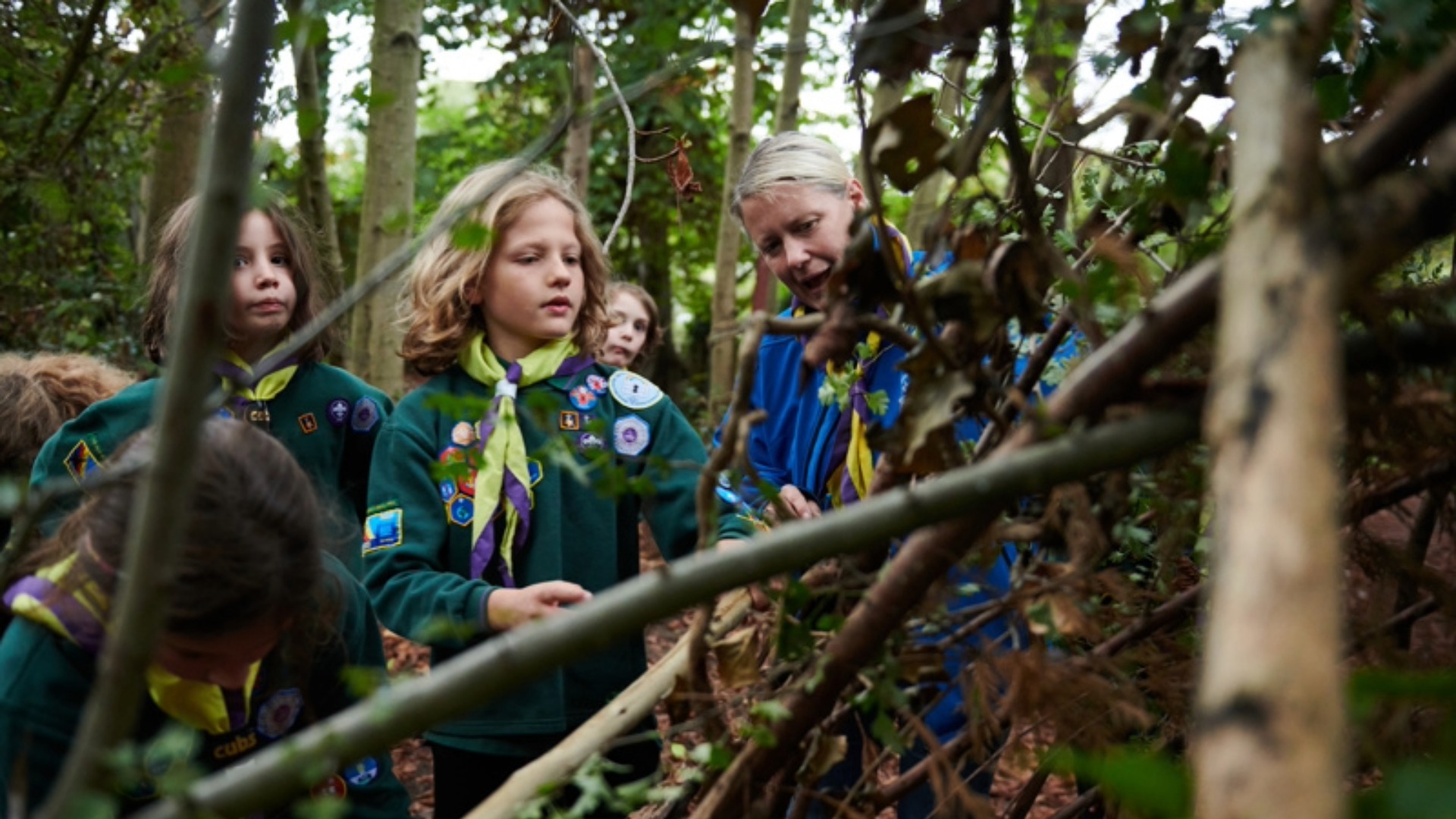 Female scout leader with scouts in the woods.