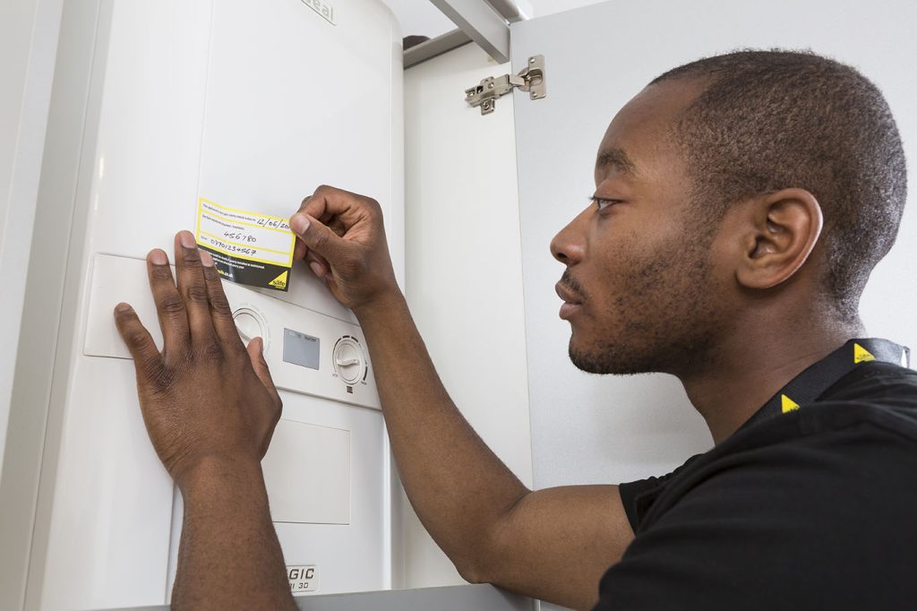 Gas Safe engineer applying Gas Safe sticker to boiler after annual service.